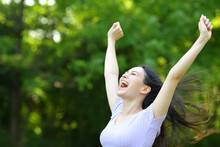 Excited Asian Woman Raising Arms In A Park