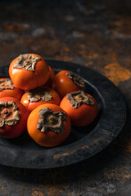 Persimmons In Black Weathered Bowl