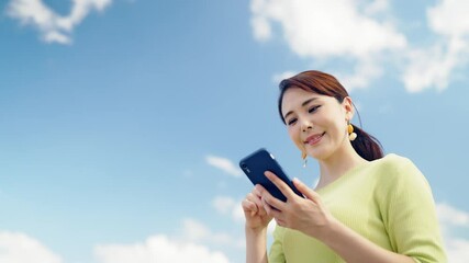 Poster - 青空を背景にスマホを使う女性