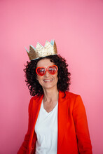 Smiling Female Professional Wearing Sunglasses And Crown Against Pink Background