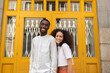© Westend61 - Smiling man and woman in front of yellow door