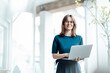 © Westend61 - Female business professional holding laptop while standing in cafe