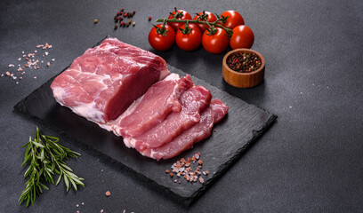 Raw pork steak on a cutting board with herbs and spices