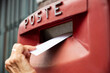 © Westend61 - Woman dropping envelope in postbox