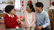 © PRPicturesProduction - thankful young couples giving Chinese new year red packet lucky money to senior mother during their visit on spring festival in a modern bright living room at home