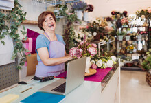 Cheerful Female Entrepreneur With Brown Hair Arranging Flowers While Standing In Shop