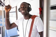 Smiling Man With Wireless Headphones Standing In Bus