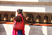 Woman Using The Prayer Wheel To Pray In Swayambunath Temple In Kathmandu, Nepal