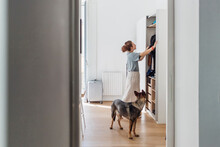 Woman Looking At Closet While Standing By Dog In Apartment