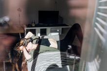 Woman Kissing German Shepherd Dog While Lying On Bed Seen From Window