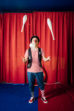 Male Performer Juggling Pins While Performing In Circus