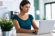© nenetus - Pretty young woman working with laptop during morning coffee in the kitchen at home.