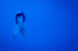 Blue prostate ribbon. Awareness of men health in November with blue prostate cancer ribbon isolated on deep blue background. November and International Mens Day.