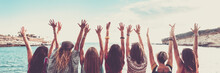 Group Of Women Viewed From Back With Arms Up For Happiness In Front Of Blue Sea Ocean Water. Vacation And Joyful People Banner