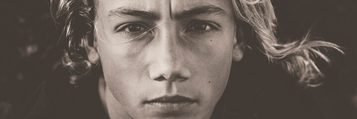 young boy model black and white portrait in banner header size. serious face of teenager