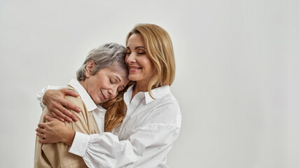 Wall Mural - loving adult daughter hug senior caucasian mother