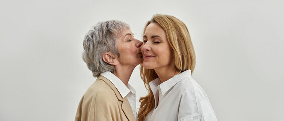 Wall Mural - banner shot of loving old mom kiss grownup daughter