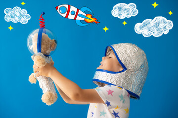 Wall Mural - Happy child astronaut playing with teddy bear