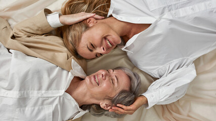 Wall Mural - wide of smiling old mom and adult daughter laugh together