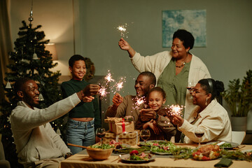 Canvas Print - Portrait of big African-American family lighting sparklers while enjoying Christmas at home together