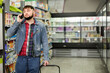 © JackF - Young guy talking on phone during shopping at grocery store