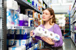 © JackF - Smiling cheerful positive woman shopping at supermarket choosing toilet paper