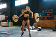 © Ezequiel Giménez/Stocksy - Strong sportswoman jumping with barbell