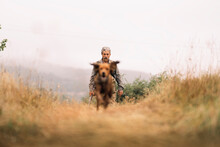 Mature Hunting Man And His Dog Chasing A Prey Across The Field.