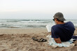 © Jimena Roquero/Stocksy - Man reading at the beach