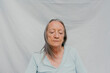 © Jimena Roquero/Stocksy - Senior woman over white background and eyes closed