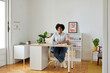 © ALTO IMAGES/Stocksy - Smiling black freelancer in home office