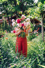 Woman Holding Flowers In Front Of Her Face In Garden