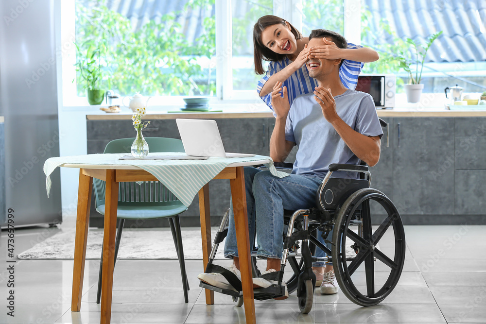 Young man with physical disability and his wife in kitchen