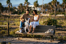 Couple Relaxing On Bench With Dog