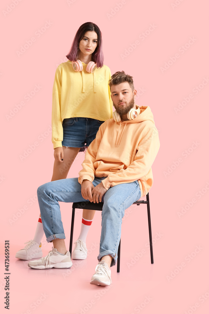 Cool young couple in hoodies on color background