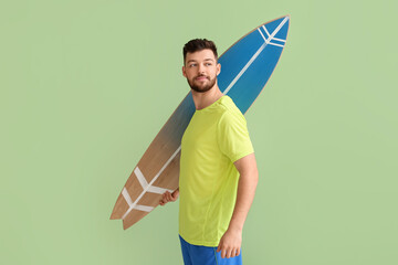 Wall Mural - Handsome bearded man with surfboard on green background