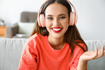 Wall Mural - Beautiful woman in headphones video chatting at home