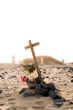 © David Prado/Stocksy - Tomb with wooden cross and flowers in beach