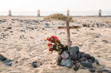 Tomb With Wooden Cross And Flowers In Beach