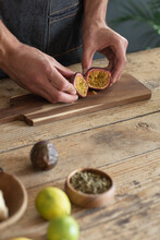 Man's Hands Opening Fresh Passion Fruit On Wooden Board