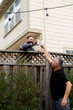 © Amy Covington/Stocksy - Two neighbors sharing beers over a fence