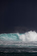 © Denni Van Huis/Stocksy - Stormy dark sky behind a big blue wave lite by the sunlight