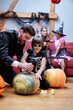 © Oleksii Syrotkin/Stocksy - Boy in skull mask with man creating pumpkin lantern