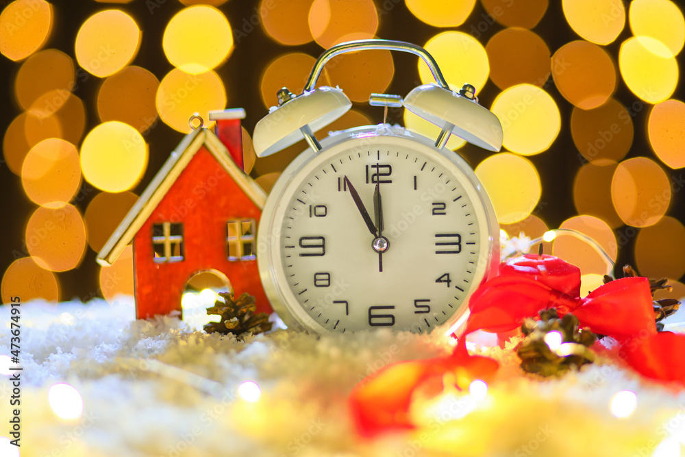 Stylish Christmas clock, decor and snow on table against blurred background