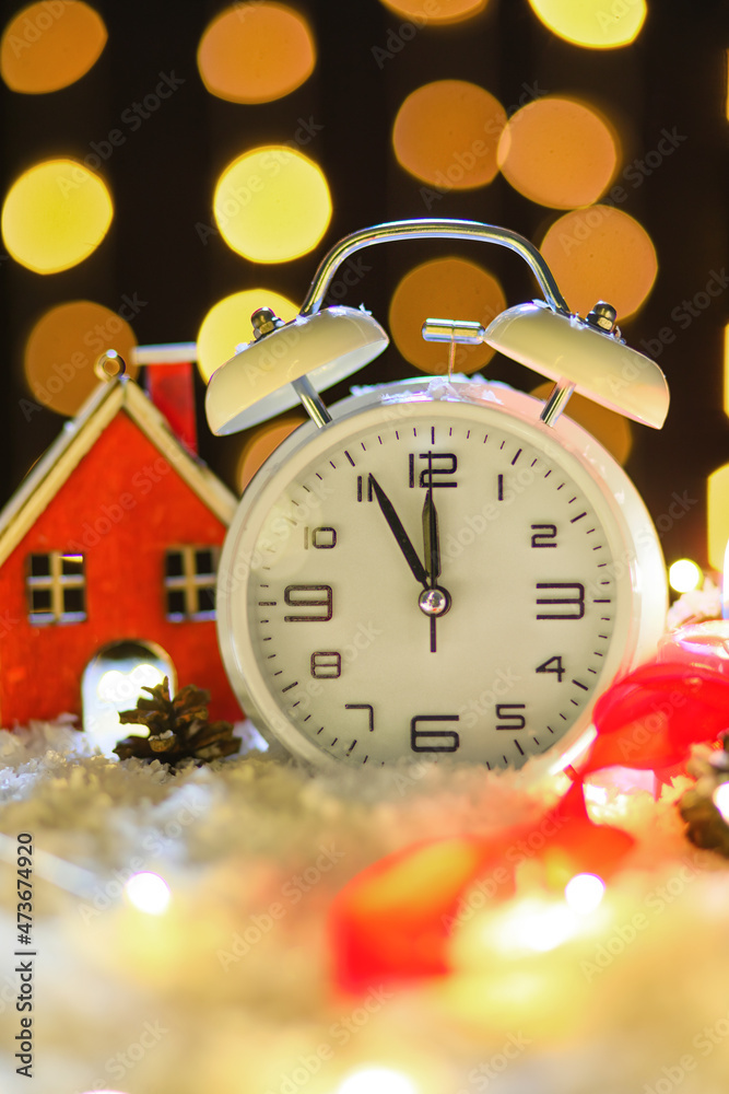 Stylish Christmas clock, decor and snow on table against blurred background