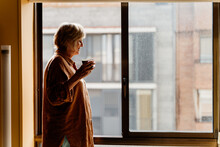 Senior Woman Drinking Coffe By The Window
