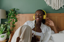A Young Smiley Black Woman Listening To Music
