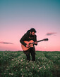 © Ibai Acevedo/Stocksy - Focussed guitarist playing at open field