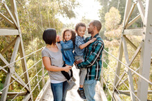 Parents With Happy Kids On Pedestrian Bridge