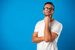 © fotofabrika - Thoughtful handsome male wearing glasses against blue background